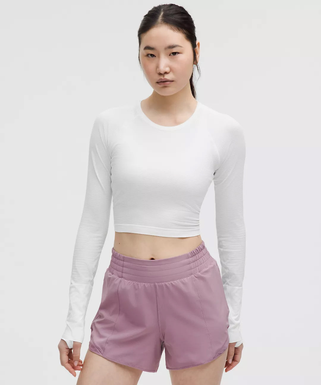 Front View of Women’s White Long Sleeve Crop Top – Natural Gas Athletic Wear – Lightweight Fitted Workout Shirt Paired with Mauve High-Waisted Shorts